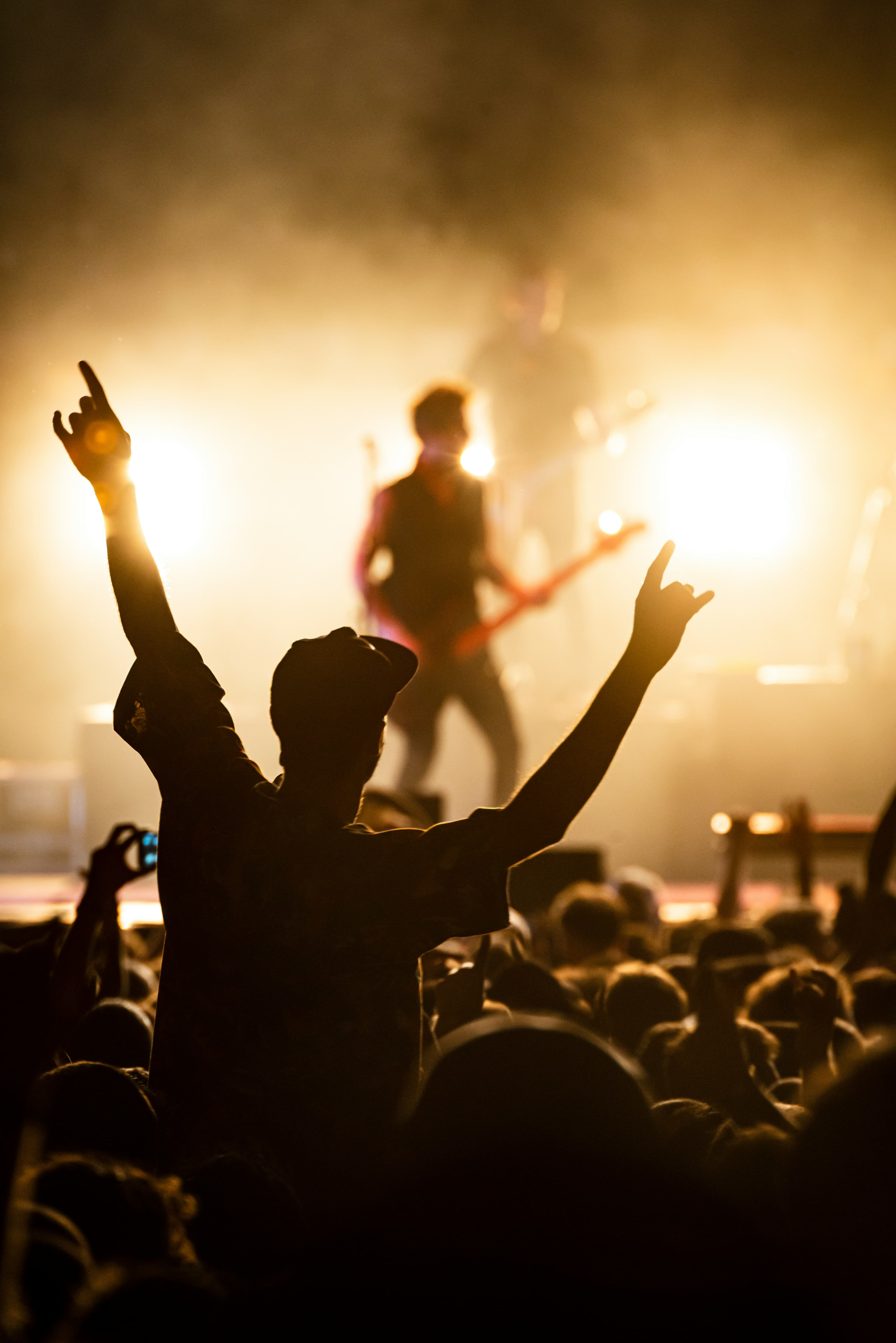 Concert crowd with raised hands in front of bright stage lights